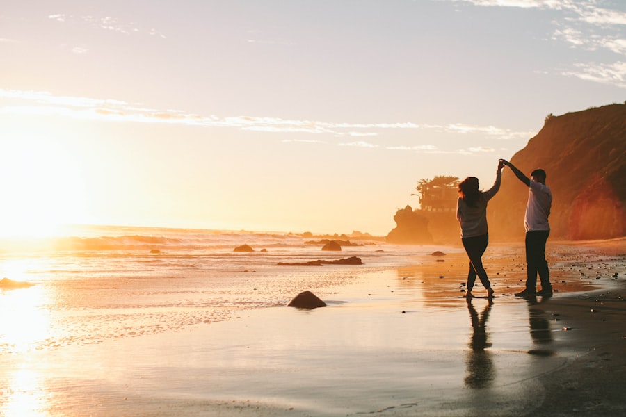Casal caminhando de mãos dadas em praia ao entardecer